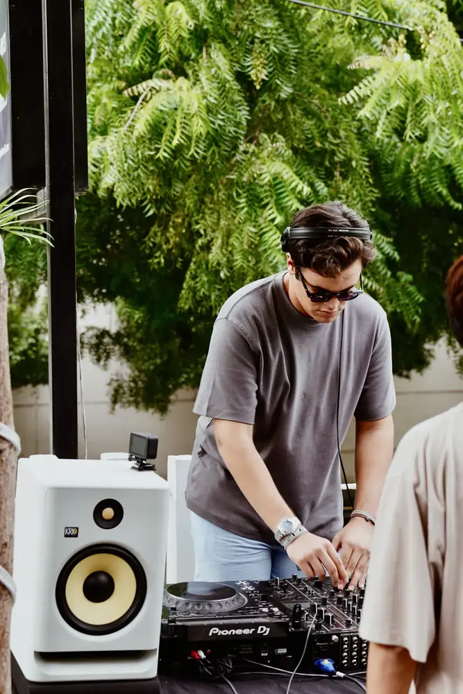DJ tocando de día junto a un parlante